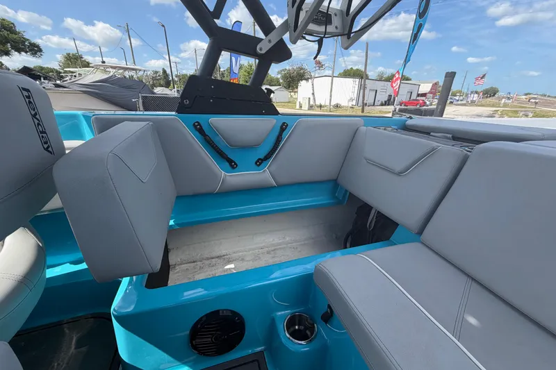 Slide: The Image of 2023 Heyday WTSurf boat interior with gray seating and blue accents under a clear sky. - 28