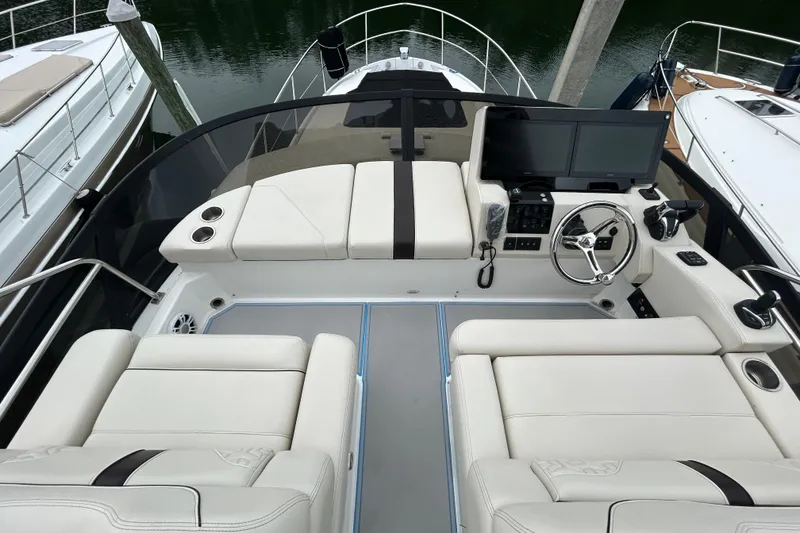 Slide: The Image of 2023 Regal 38 FXO boat cockpit with dual screens, steering wheel, and luxurious seating. - 21