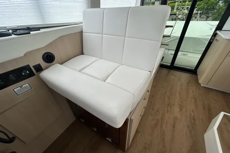 Slide: The Image of Luxurious white seating inside 2023 Regal 38 FXO yacht, featuring modern design and wood flooring. - 62