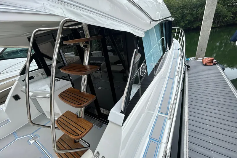 Slide: The Image of 2023 Regal 38 FXO yacht with sleek design and wooden steps, docked by the water. - 39