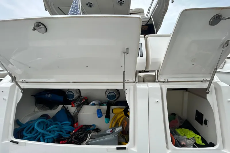 Slide: The Image of Open storage compartments on a 2023 Regal 38 FXO boat, revealing various boating equipment. - 13
