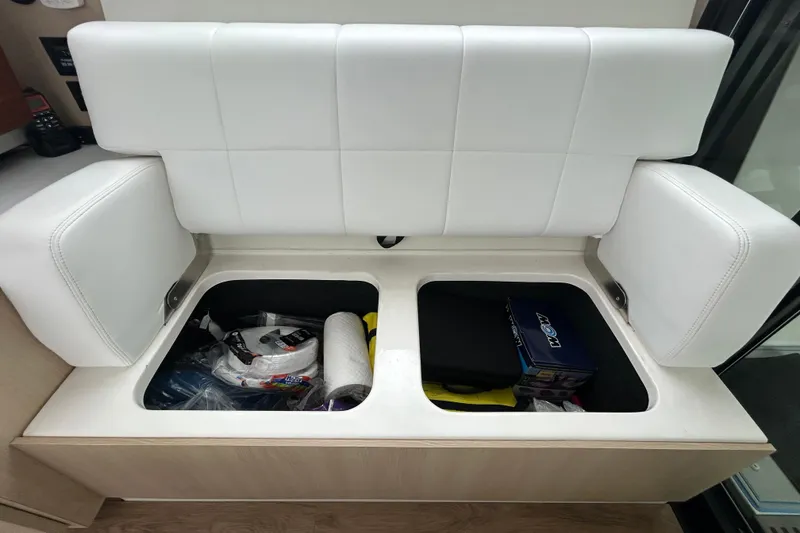 Slide: The Image of 2023 Regal 38 FXO boat interior storage compartment with white cushioned seating. - 57