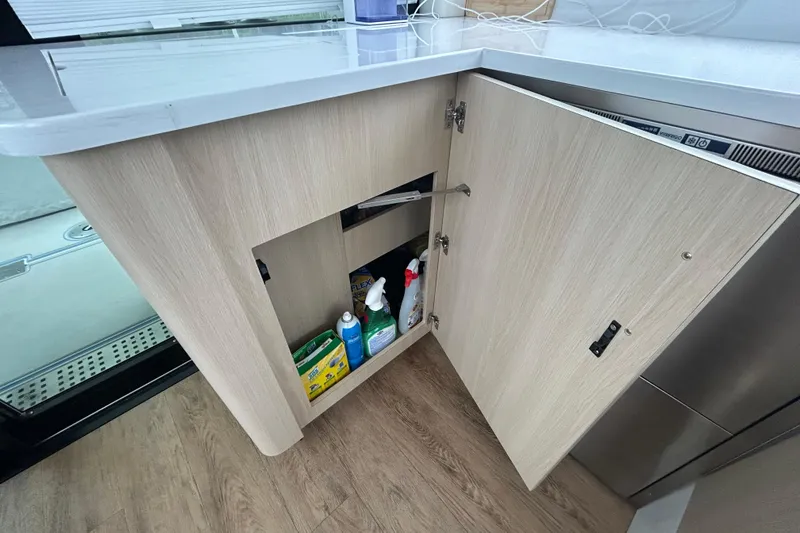 Slide: The Image of Open cabinet in 2023 Regal 38 FXO yacht, showcasing cleaning supplies and modern interior design. - 81