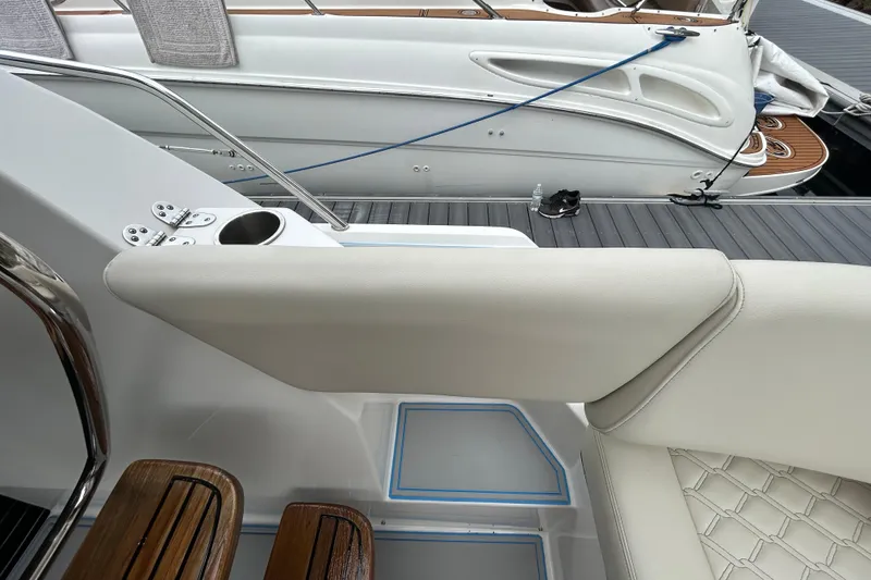 Slide: The Image of 2023 Regal 38 FXO boat interior with white seating and wooden accents at a marina. - 53