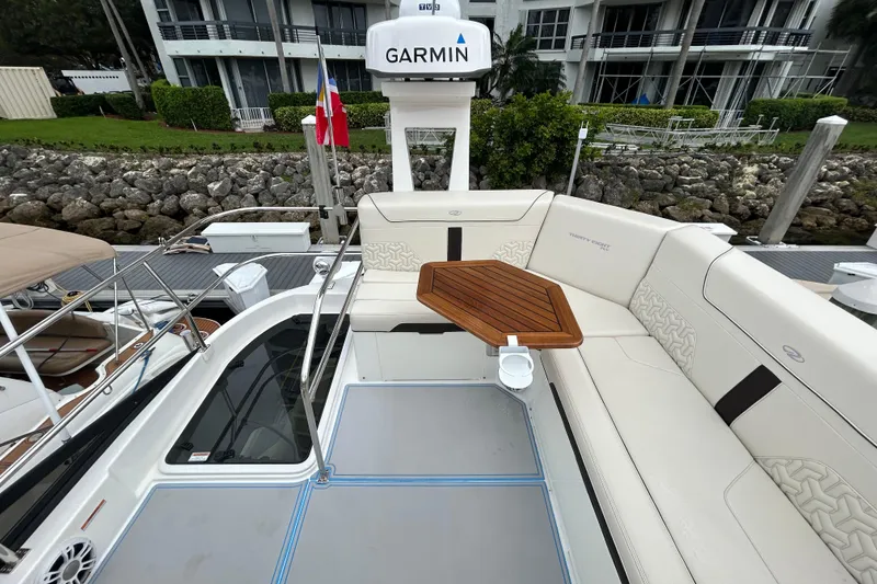Slide: The Image of 2023 Regal 38 FXO yacht with elegant seating and wooden table, docked near modern buildings. - 38
