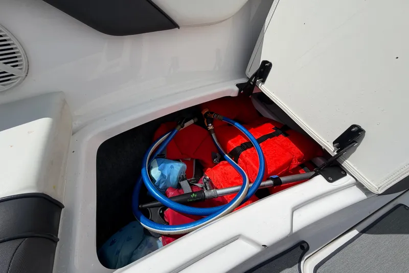 Slide: The Image of Storage compartment in 2022 Yamaha AR210 boat with life jacket and hose. - 45