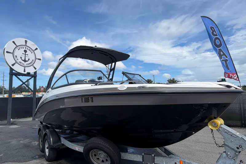 The Image of 2022 Yamaha AR210 boat on trailer at dealership, blue sky background. - 0