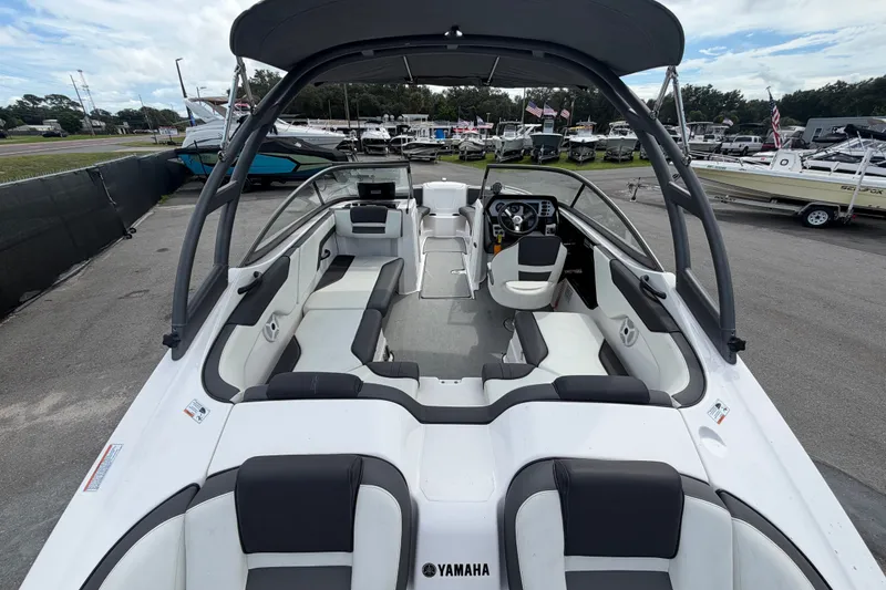 Slide: The Image of 2022 Yamaha Boats AR210 interior view, showcasing seating and helm, parked in a marina. - 10