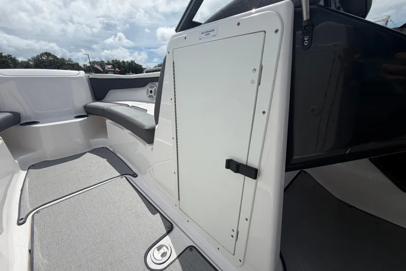 Slide: The Image of 2022 Yamaha Boats AR210 interior with seating and storage compartment under a cloudy sky. - 36