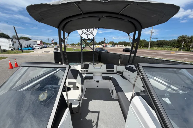 Slide: The Image of 2022 Yamaha Boats AR210 interior with seating and canopy, parked outdoors. - 49