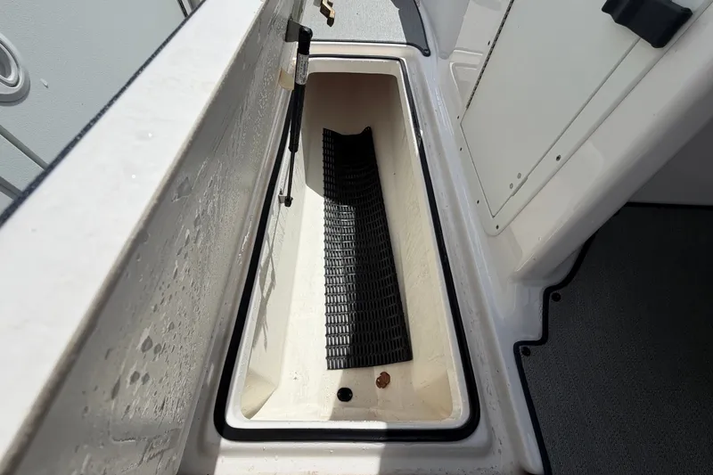 Slide: The Image of 2022 Yamaha AR210 boat storage compartment with black mat and hydraulic lift. - 32