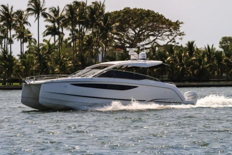 Slide: The Image of Manufacturer Provided Image: 2025 Four Winns TH36 yacht cruising on a tropical waterway with palm trees in the background. - 3