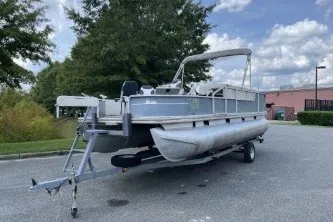 Slide: The Image of 2002 Fisher Freedom 220 DLX FISH pontoon boat on trailer, parked outdoors. - 2