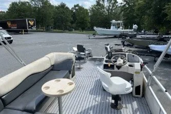 Slide: The Image of 2002 Fisher Freedom 220 DLX FISH pontoon boat with seating and steering console in a parking lot. - 9