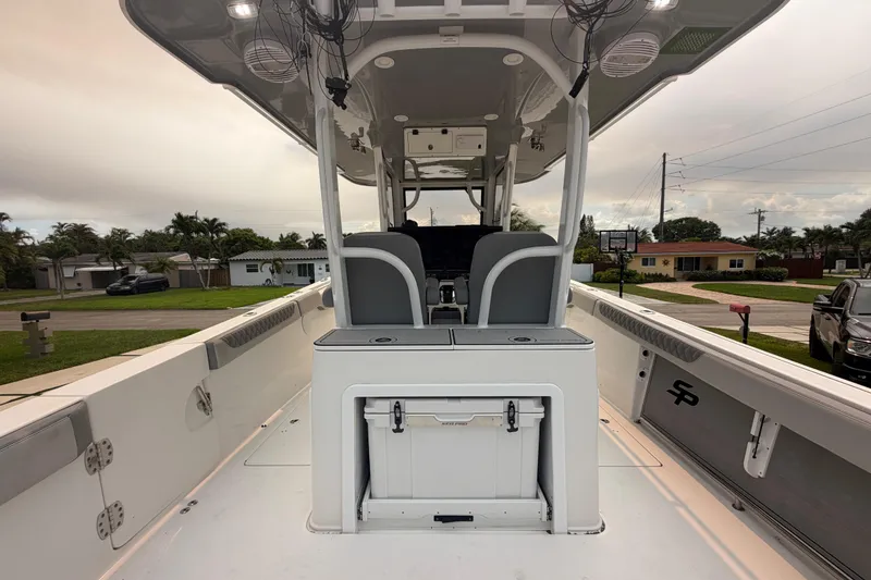 Slide: The Image of 2023 Sea Pro 320 DLX Offshore boat interior with seating and storage, parked in a residential area. - 13