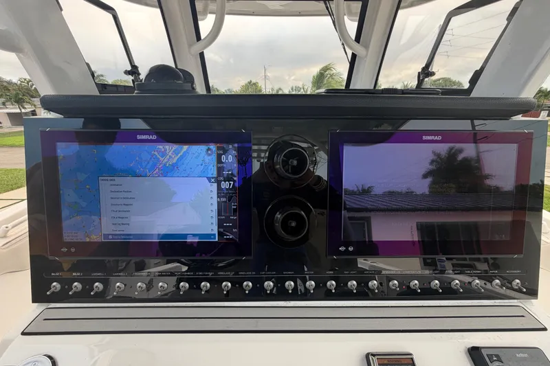 Slide: The Image of 2023 Sea Pro 320 DLX Offshore dashboard with dual Simrad displays and control switches. - 19