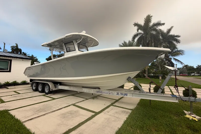 Slide: The Image of 2023 Sea Pro 320 DLX Offshore boat on trailer, parked in a tropical setting. - 2