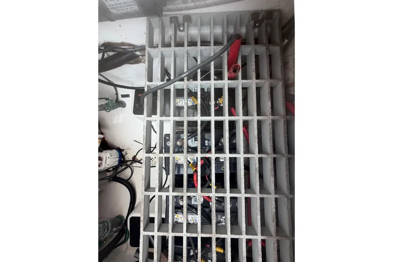 Slide: The Image of Battery compartment of 2023 Sea Pro 320 DLX Offshore boat, featuring wiring and grid cover. - 57