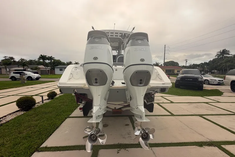 Slide: The Image of 2023 Sea Pro 320 DLX Offshore boat with dual Suzuki 350 outboard engines, parked in driveway. - 4