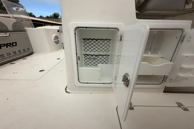 Slide: The Image of 2023 Sea Pro 320 DLX Offshore boat storage compartment with open door and netted shelves. - 61