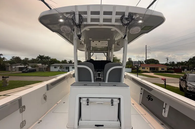 Slide: The Image of 2023 Sea Pro 320 DLX Offshore boat interior with seating and storage, parked in a residential area. - 14