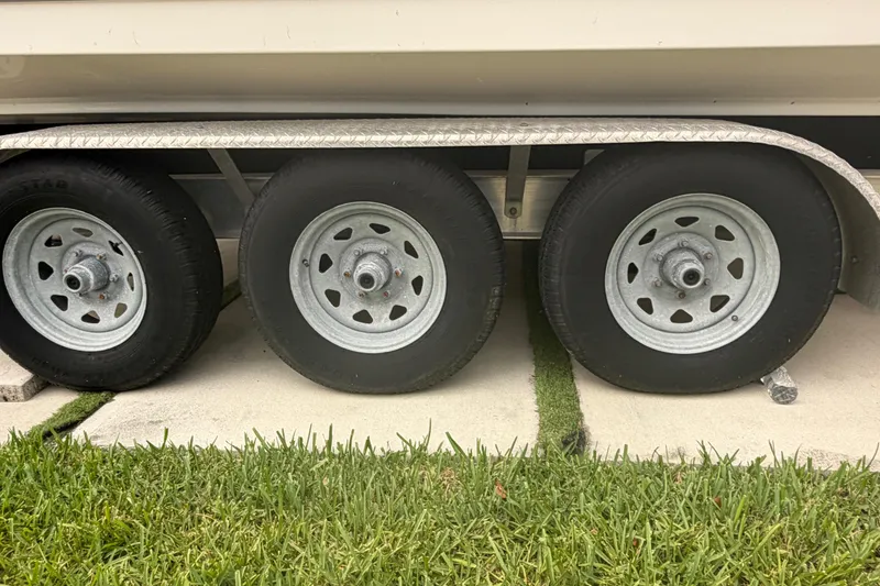 Slide: The Image of Trailer wheels of a 2023 Sea Pro 320 DLX Offshore boat on grass. - 65