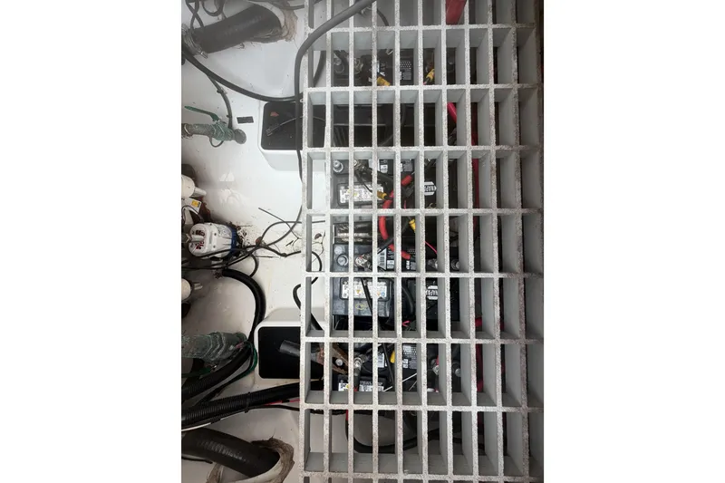 Slide: The Image of Battery compartment of 2023 Sea Pro 320 DLX Offshore boat, featuring wiring and grid cover. - 58