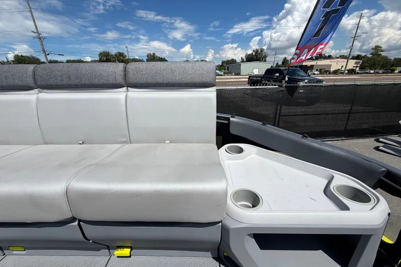 Slide: The Image of 2023 Sea-Doo Switch Cruise 21 interior with gray seating and cup holders under a blue sky. - 52