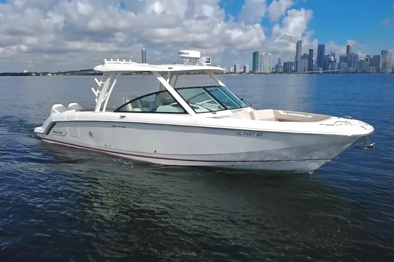 Slide: The Image of 2021 Boston Whaler 320 Vantage boat cruising on water with city skyline backdrop. - 1