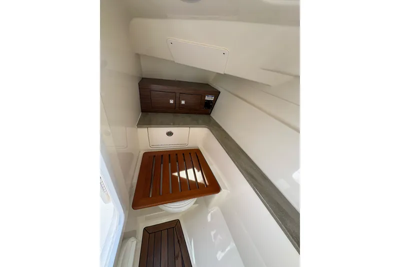 Slide: The Image of Interior of 2021 Boston Whaler 320 Vantage boat, featuring wooden accents and storage compartments. - 98