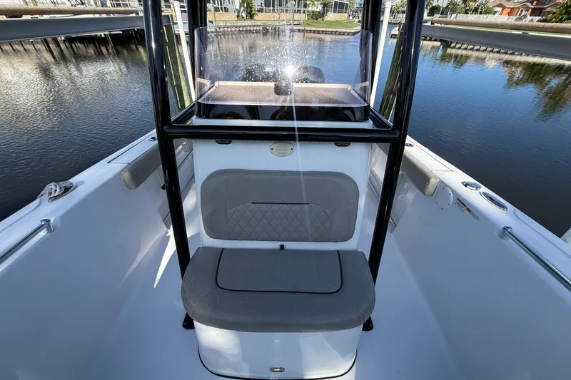 Slide: The Image of 2023 Sportsman Heritage 241 Center Console boat interior with seating, docked by calm water. - 46