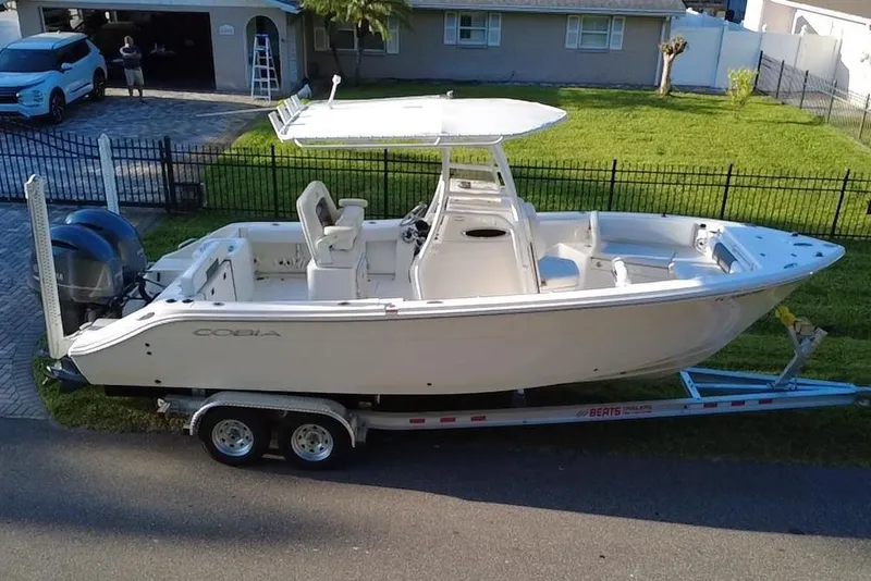 Slide: The Image of 2021 Cobia 240 Center Console boat on trailer in residential driveway. - 1