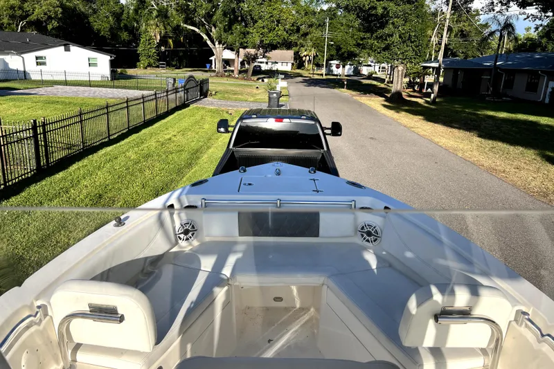 Slide: The Image of 2021 Cobia 240 Center Console boat being towed by a truck on a suburban street. - 60