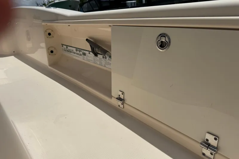 Slide: The Image of 2021 Grady-White 251 Coastal Explorer boat storage compartment with fish ruler and latch. - 53