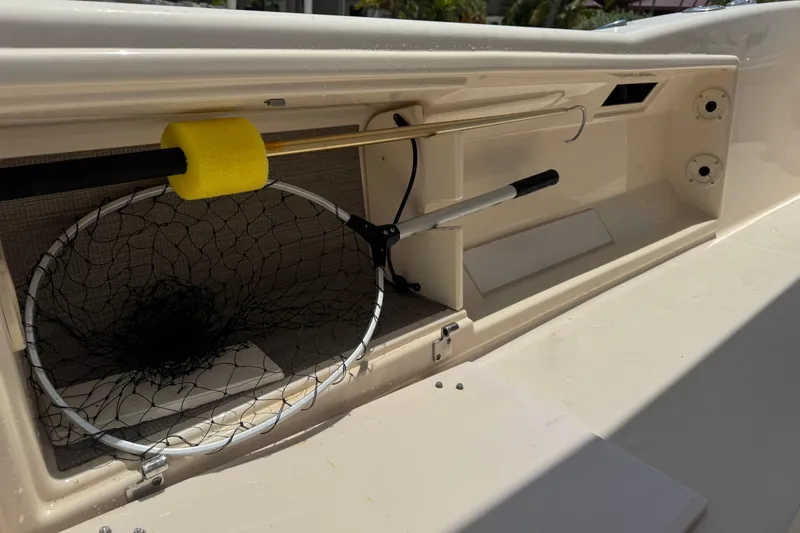 Slide: The Image of Storage compartment on 2021 Grady-White 251 Coastal Explorer with fishing net and gaff hook. - 49