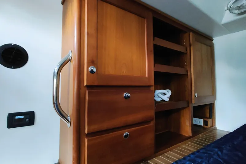 Slide: The Image of Wooden cabinets in a boat cabin with shelves and drawers, next to a blue bed. - 43