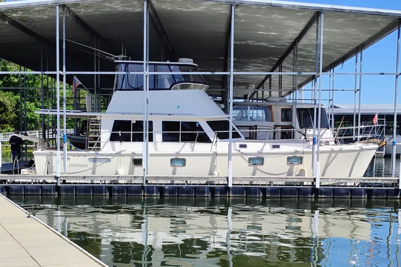 The Image of A 2009 Maine Cat P-47 is docked under a covered area. The boat features a spacious upper deck. - 1