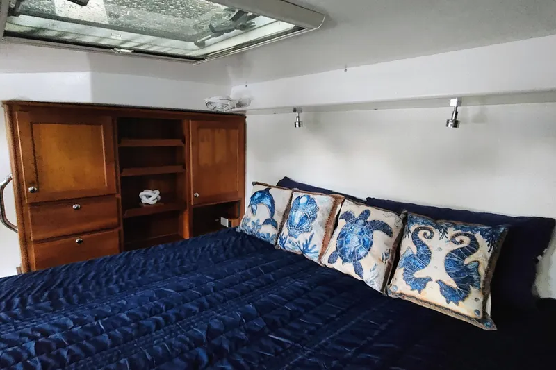 Slide: The Image of Cabin with a cozy bed, blue sea-themed pillows, and a wooden cabinet. - 41
