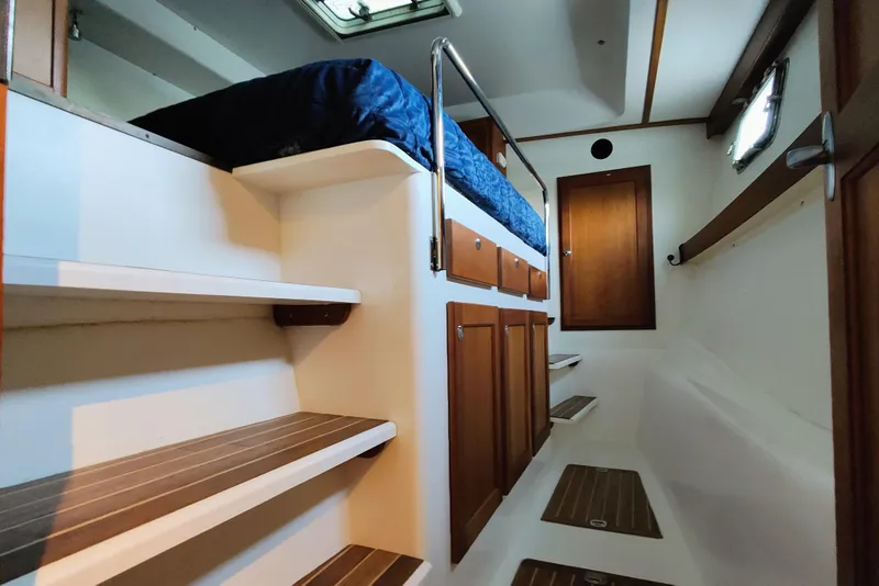 Slide: The Image of Interior of a 2009 Maine Cat P-47 with wood paneling and a blue bedspread. - 39