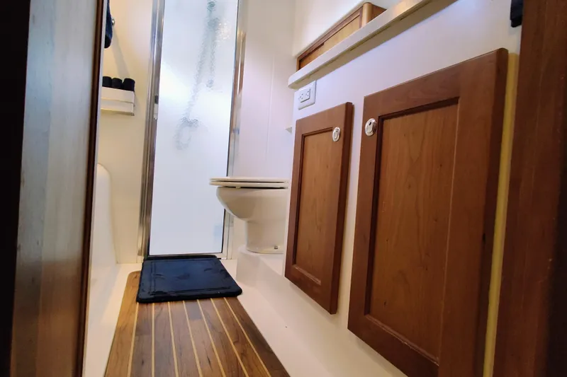 Slide: The Image of The image shows a bathroom with wooden floors and cabinets, a toilet, and a shower stall. - 48