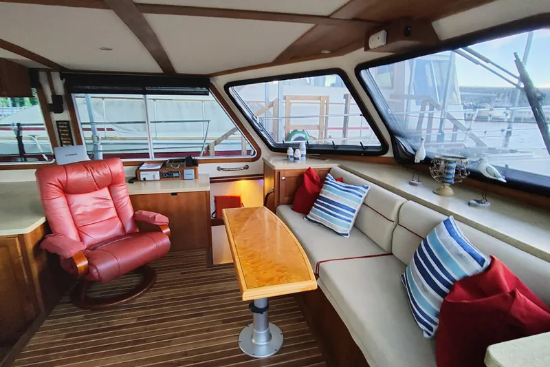 Slide: The Image of Interior of a yacht with a red chair, wooden table, and striped cushions. - 34
