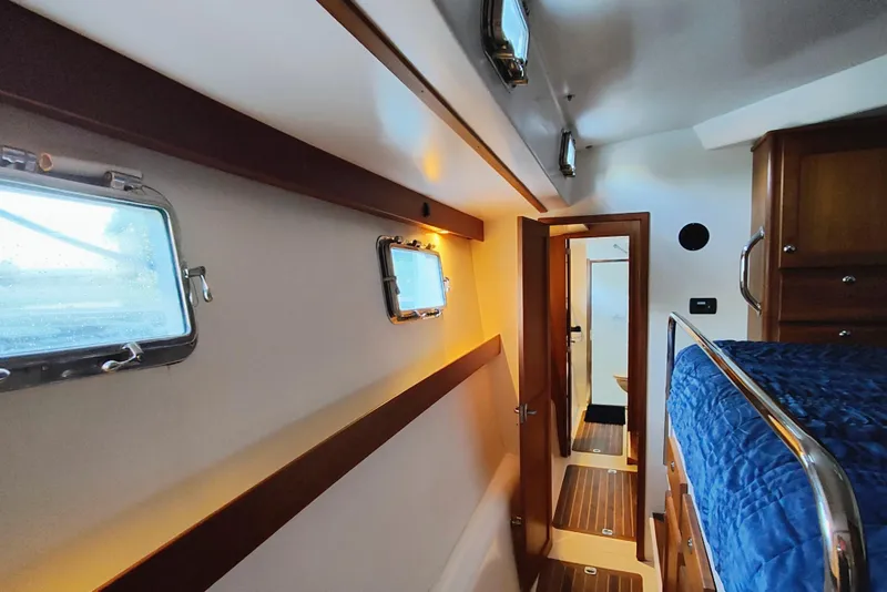 Slide: The Image of Interior of a 2009 Maine Cat P-47 with wood accents and a blue bedspread. - 42