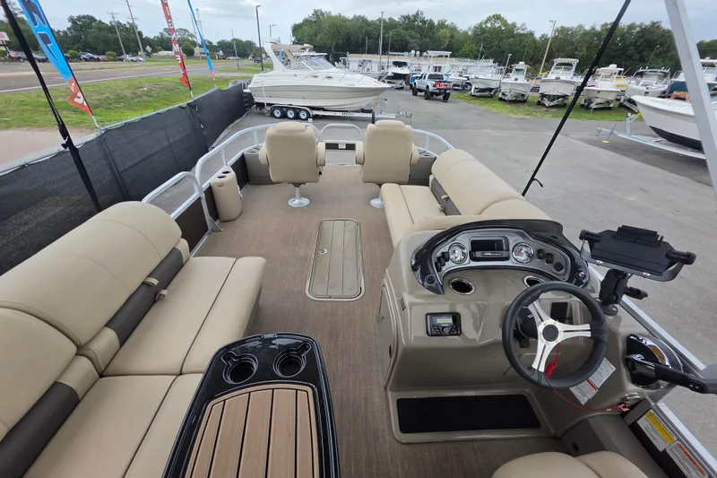 Slide: The Image of 2023 Sun Tracker Bass Buggy 18 DLX pontoon boat interior with beige seating and steering console. - 18