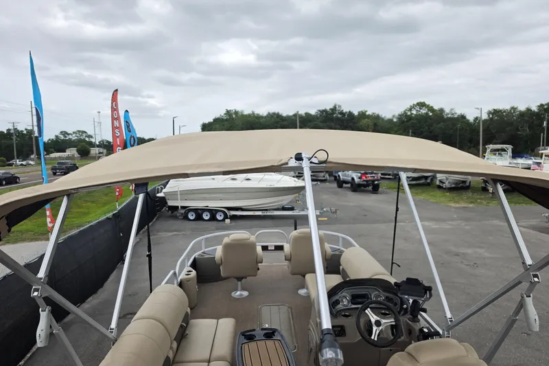 Slide: The Image of 2023 Sun Tracker Bass Buggy 18 DLX pontoon boat with canopy, parked outdoors. - 60