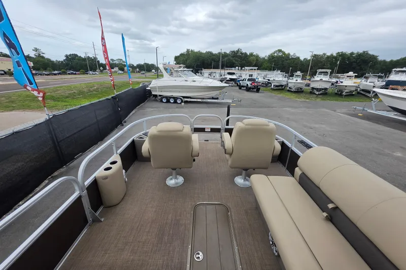 Slide: The Image of 2023 Sun Tracker Bass Buggy 18 DLX pontoon boat at a dealership, showcasing seating and deck layout. - 28