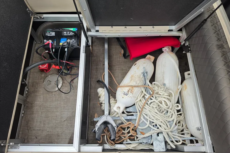 Slide: The Image of Storage compartment of 2023 Sun Tracker Bass Buggy 18 DLX with battery, ropes, and fenders. - 47