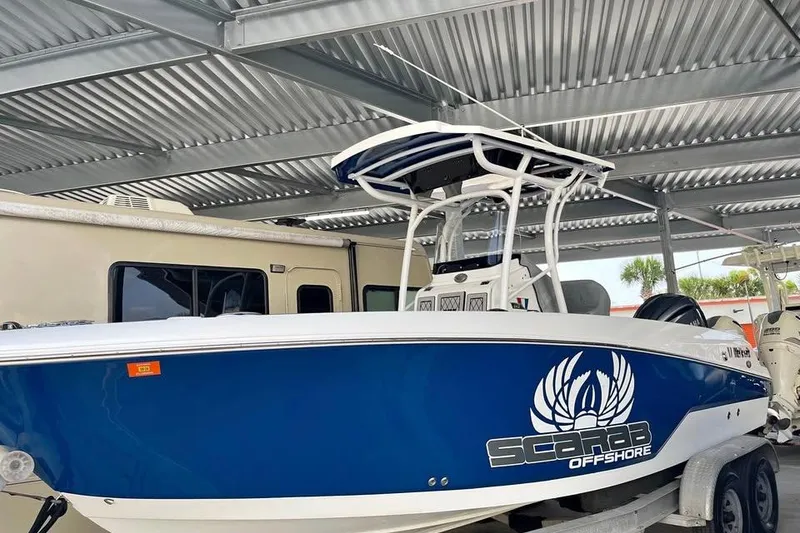 Slide: The Image of 2023 Wellcraft 242 Fisherman boat in blue, parked under a metal canopy. - 1