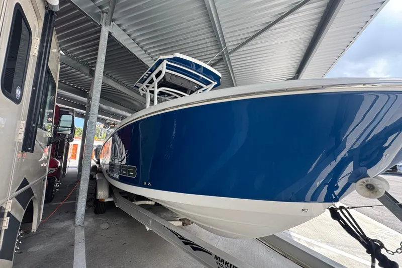 Slide: The Image of 2023 Wellcraft 242 Fisherman boat in storage, blue hull, parked under a metal roof. - 20