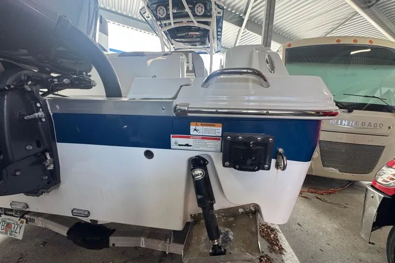 Slide: The Image of 2023 Wellcraft 242 Fisherman boat rear view in storage, featuring motor and warning label. - 8