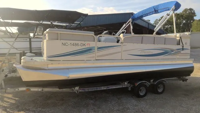 The Image of A 2008 Manitou OASIS 20 pontoon boat on a trailer, featuring a blue canopy. - 1
